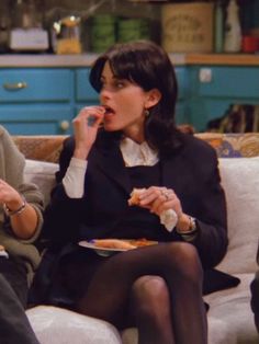 two women sitting on a couch eating pizza