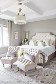 a bedroom with a large bed, two chairs and a chandelier hanging from the ceiling