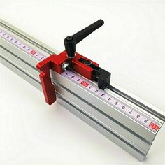 a red and black tool is on top of a metal ruler that has been placed in front of it