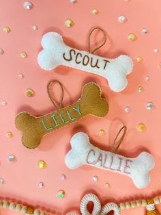 three dog bone ornaments on a pink background