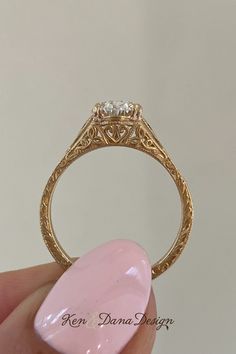 a close up of a person's hand holding a ring with a pink stone