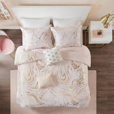 an aerial view of a bed with white and gold comforter sets, pillows and decorative items