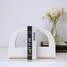 a white bookend sitting on top of a table next to a vase filled with flowers