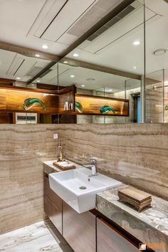 a bathroom with marble counter tops and wooden cabinetry, along with a large mirror above the sink