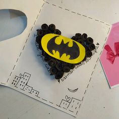 a batman brooch sitting on top of a piece of paper next to a bow