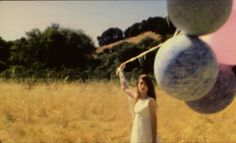 a woman in a white dress is holding some balloons