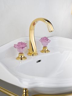 a white sink with gold fixtures and pink flowers