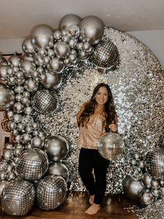 a woman standing in front of silver disco balls