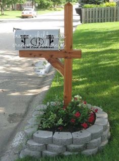 a wooden cross sitting on the side of a road next to a flower pot filled with flowers