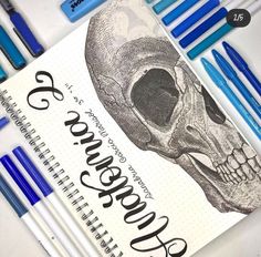 some pens are laying next to a notebook with a skull on it and the title is 25 years old