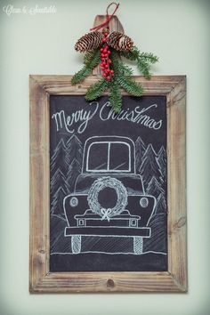 a chalkboard with a christmas truck drawn on it and pine cones hanging from the top