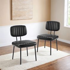 two black chairs sitting on top of a white rug