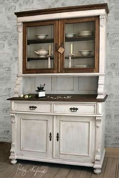 an old fashioned china cabinet with glass doors and wood trimmings on the top