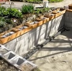 an unfinished concrete retaining wall with plants growing in it