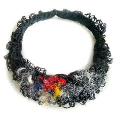 a multicolored necklace is shown on a white surface, with black yarn and beads