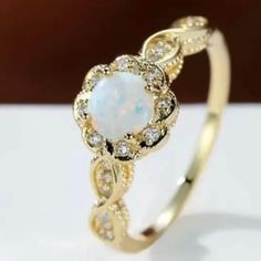 a white opal and diamond ring sitting on top of a table