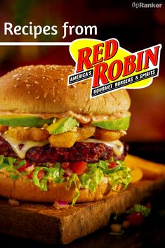 a large sandwich sitting on top of a wooden cutting board next to a sign that reads, recipes from red robin