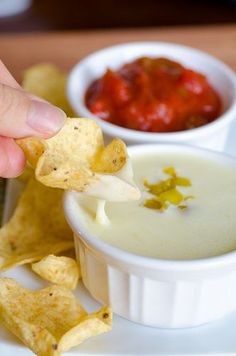 a person dipping tortilla chips into a bowl of dip