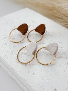 three pairs of gold and white earrings sitting on top of a table next to fur