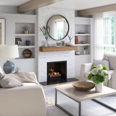 a living room filled with furniture and a fire place in front of a mirror on the wall