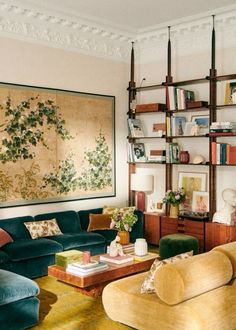 a living room filled with furniture and bookshelves next to a painting on the wall