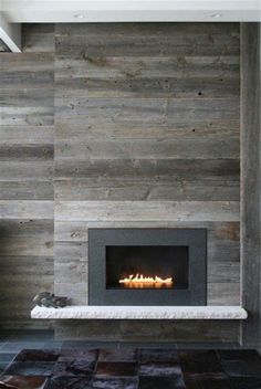 a modern fireplace in a living room with wood paneling on the walls and floor