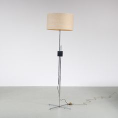 a floor lamp with a beige shade on it