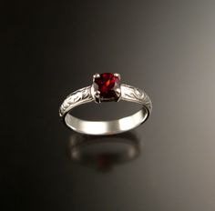 a close up of a ring with a red stone in it on a black surface