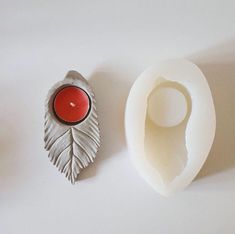 an egg shell with a red candle in it next to a white object on a table