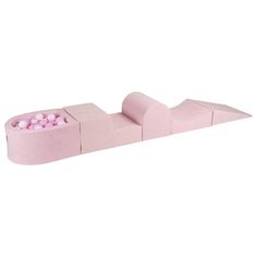 a pink bed with balls in it on top of a white surface and the mattress is made out of cardboard