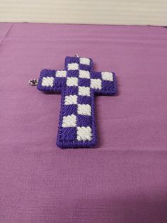 a purple and white crocheted cross sitting on top of a purple table cloth