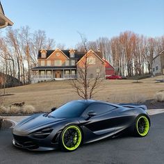 a black and yellow sports car parked in front of a large house on the street