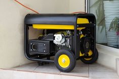 a yellow and black portable generator sitting on the ground next to a window with plants in it