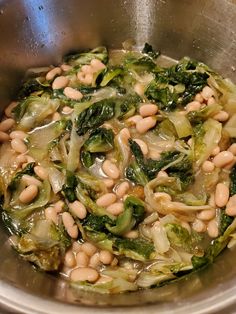 a pot filled with beans and greens on top of a stove