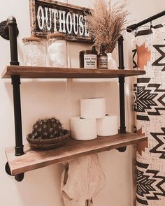 a shelf with toilet paper, candles and other items on it in a bathroom area