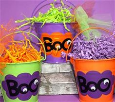 three buckets filled with halloween decorations on top of a wooden table and purple background