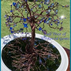 a small tree with blue glass beads on it's branches in a white pot