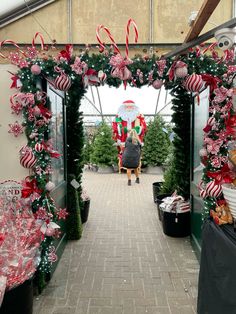 a woman is standing in the middle of an outdoor christmas decoration area with candy canes and decorations