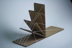 an origami sculpture made out of cardboard and string, on a white background