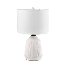 a white table lamp with a white shade on the base and a light bulb attached to it