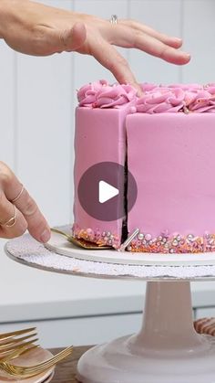 a woman is decorating a pink cake with sprinkles