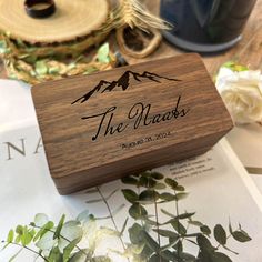 a wooden box sitting on top of a table filled with flowers and greenery next to a mug