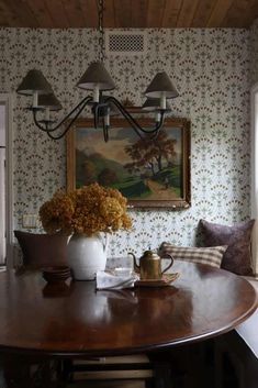 a dining room table and chairs with flowers in vases on the table next to it