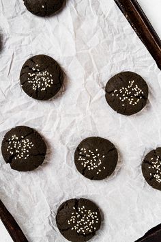 chocolate cookies with white sprinkles are on a sheet of parchmented paper