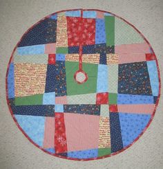 a round quilted table top with various colored squares and circles on the center piece