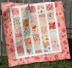 a quilt is hanging on a fence outside in the grass and it's not too bright