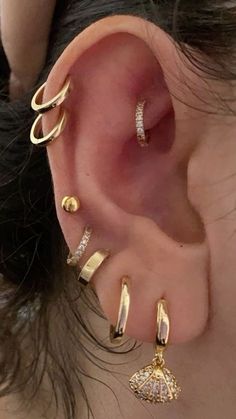 an ear with three different types of piercings on it's sides and one is gold