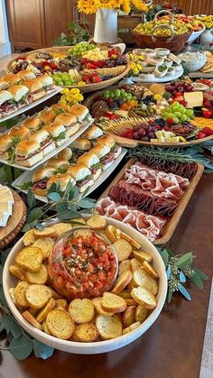 a table filled with lots of different types of sandwiches and appetizers on trays