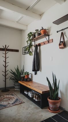 a room with plants and shoes hanging on the wall next to a wooden bench in front of a coat rack