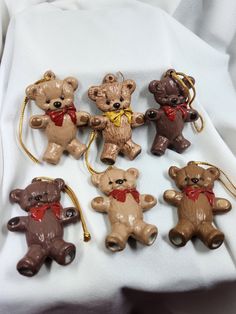 six brown teddy bears with red bows on their heads and tails are hanging from gold - plated chains